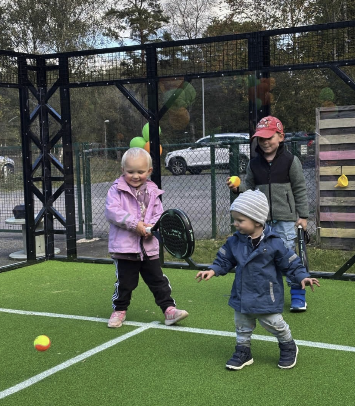 Barn som leker med bollar på padelbana.